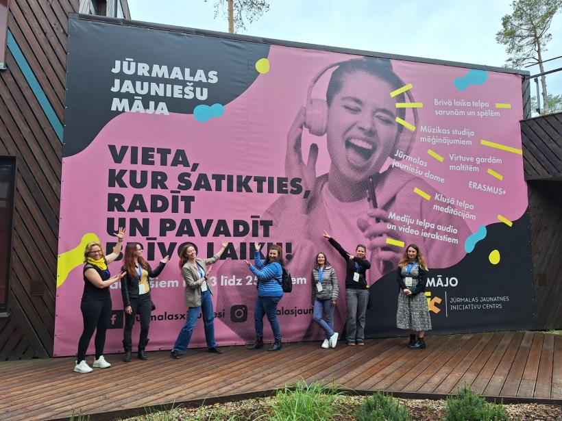 cilvēku grupa pie krāsaina plakāta