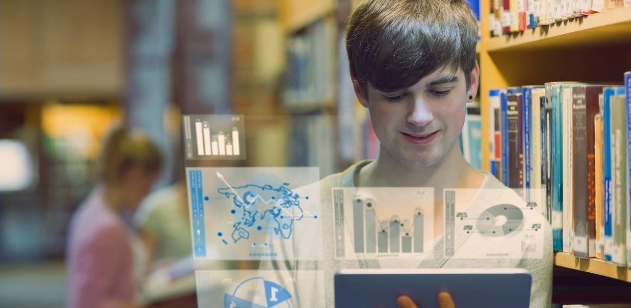 Students bibliotēkā ar atvērtu digitālo grāmatu