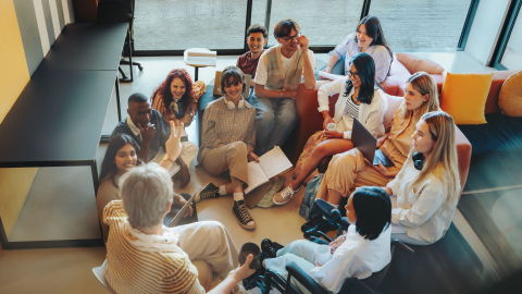 jauniešu grupa sēž kopā ar skolotāju, diskutē