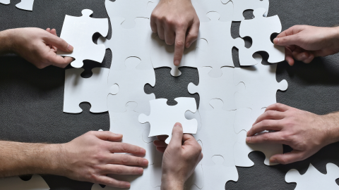Balti puzles gabaliņi tiek likti kopā, komandas darbs